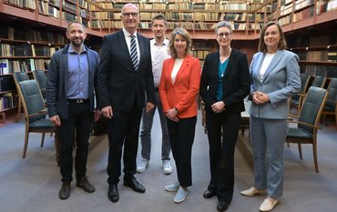 Group photo in the Historical Library: Six people standing in a room with historical books on tall shelves.