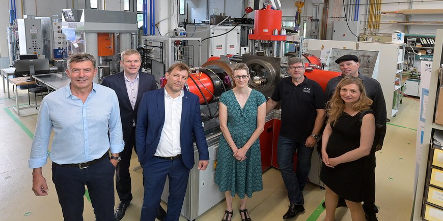 Group photo with 7 people in front of a new metal plant in a large laboratory hall.