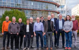 Group photo of 12 people in front of a DFN building.