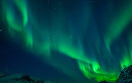 Green aurora borealis, in the bottom right corner mountain peak