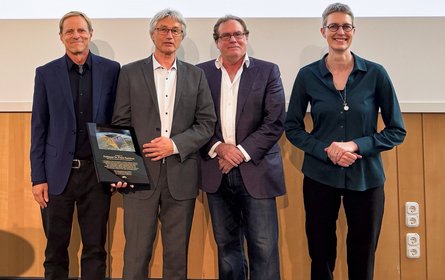 Einfaches Gruppenbild vor einer Wand von vier Personen frontal.