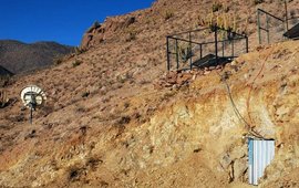 The photo shows a dry mountain landscape with photovoltaic systems