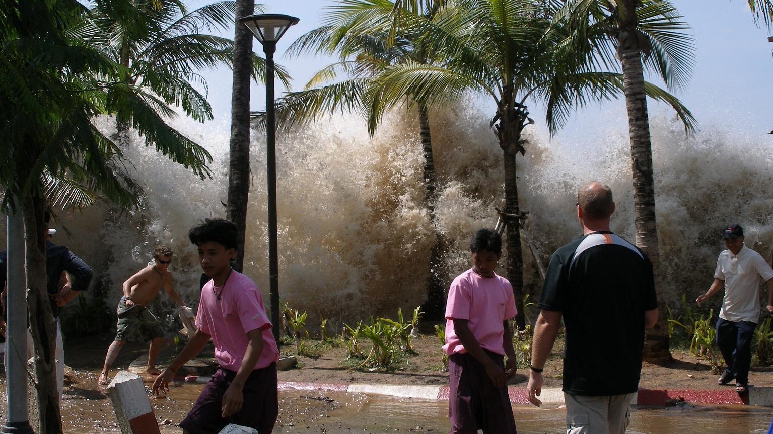 People on the beach, a tsunami wave reaches them.