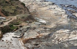 Das Bild zeigt einen steinigen Küstenabschnitt, der teilweise nicht mehr mit Wasser bedeckt ist