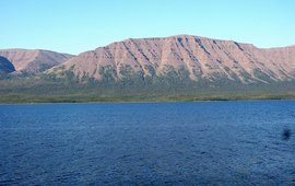 Das Bild zeigt Wasser mit einem rötlichen Berg dahinter