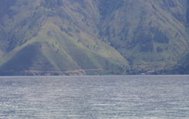 Das Bild zeigt grün bewachsene Berge mit Wasser