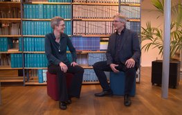 Both scientists sitting on stools in front of a wall of books in the Telegrafenberg library