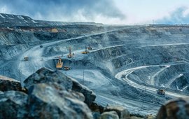 An open pit mine: grey rock, ramps, huge truck loaders driving on them.