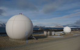 2 große Kugeln in der Landschaft. Es handelt sich um die Satellitenempfangsstationen, im Hintergrund Berge