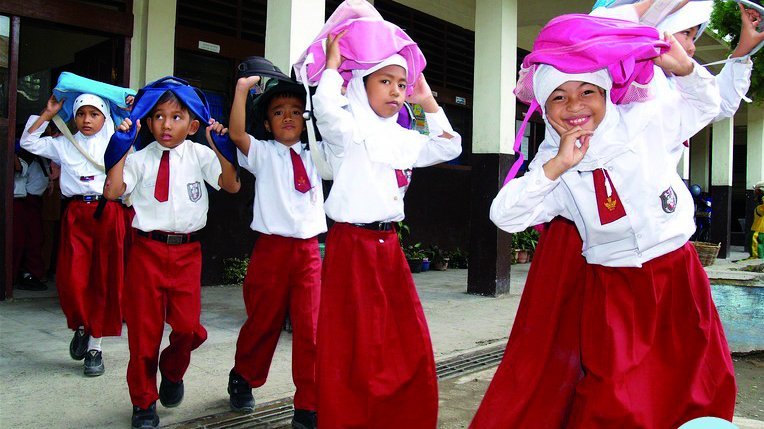 Children wearing their backpacks on their heads as part of an early warning exercise for protection.