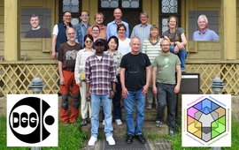 Gruppenfoto auf der Treppe vor einem Holzhaus; rechts und links die Logos von DGG und AG Geomagnetik.