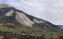 A mountain with a boulder field, which is now sliding down, and the village below.