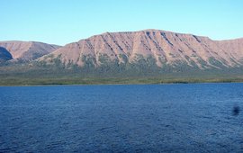 The picture shows water with a reddish mountain behind it