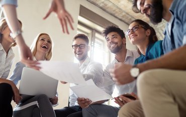 Gruppe lachender Menschen bei der Zusammenarbeit