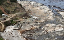 The picture shows a rocky section of coastline that is partially no longer covered with water