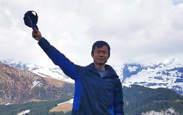 Kai Deng is standing in front of a mountain area